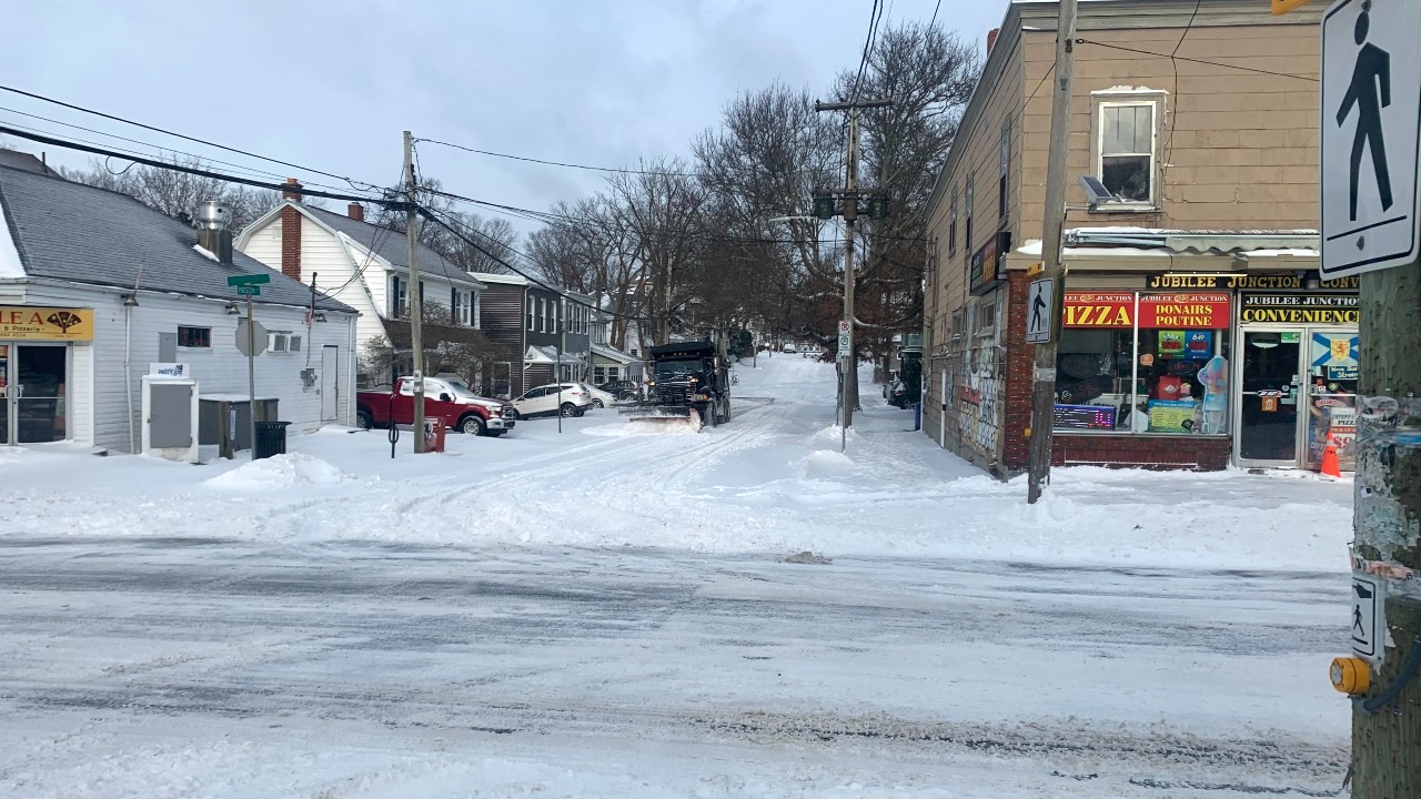 A snow plow is seen plowing a street.
