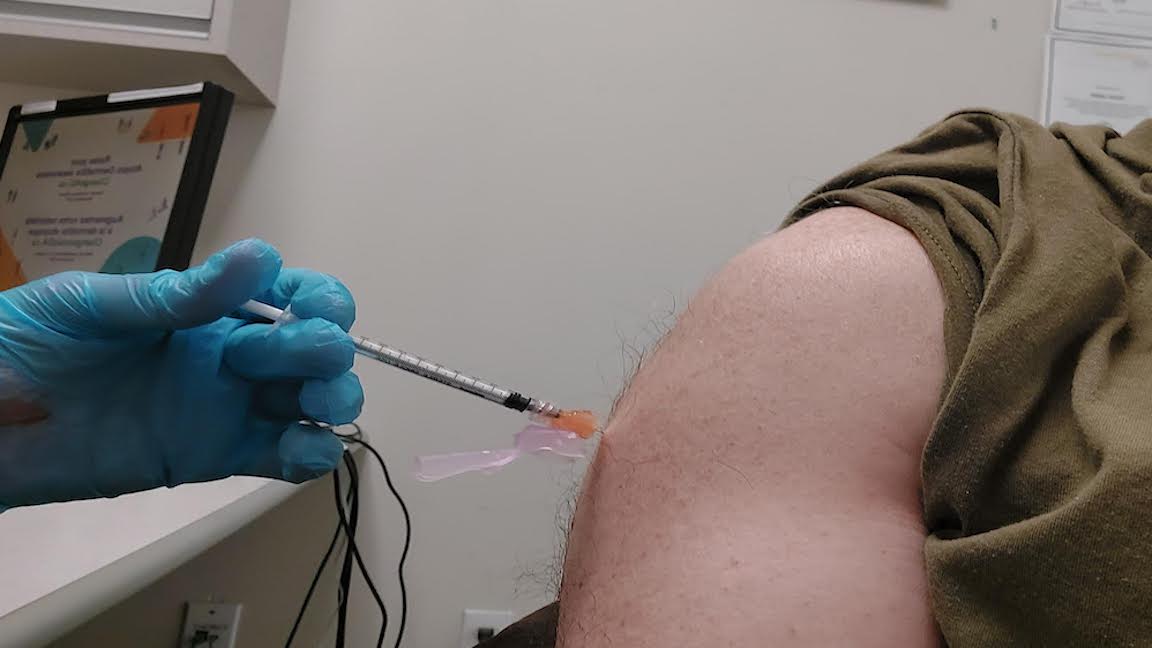 A vaccine booster shot is administered to someone's arm.