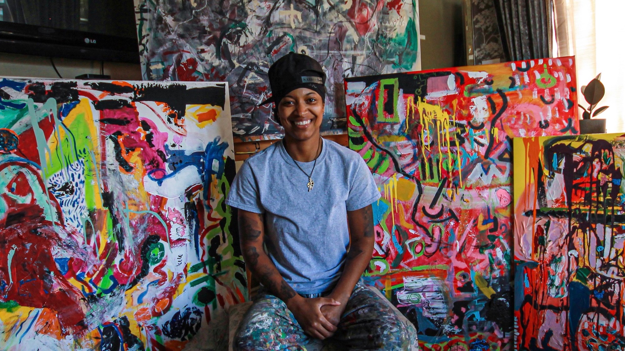 Mireka Starr sits in front of her artwork. Her painting style is inspired by Davyd Whaley, an American abstract artist who helped her realize her passion for art.