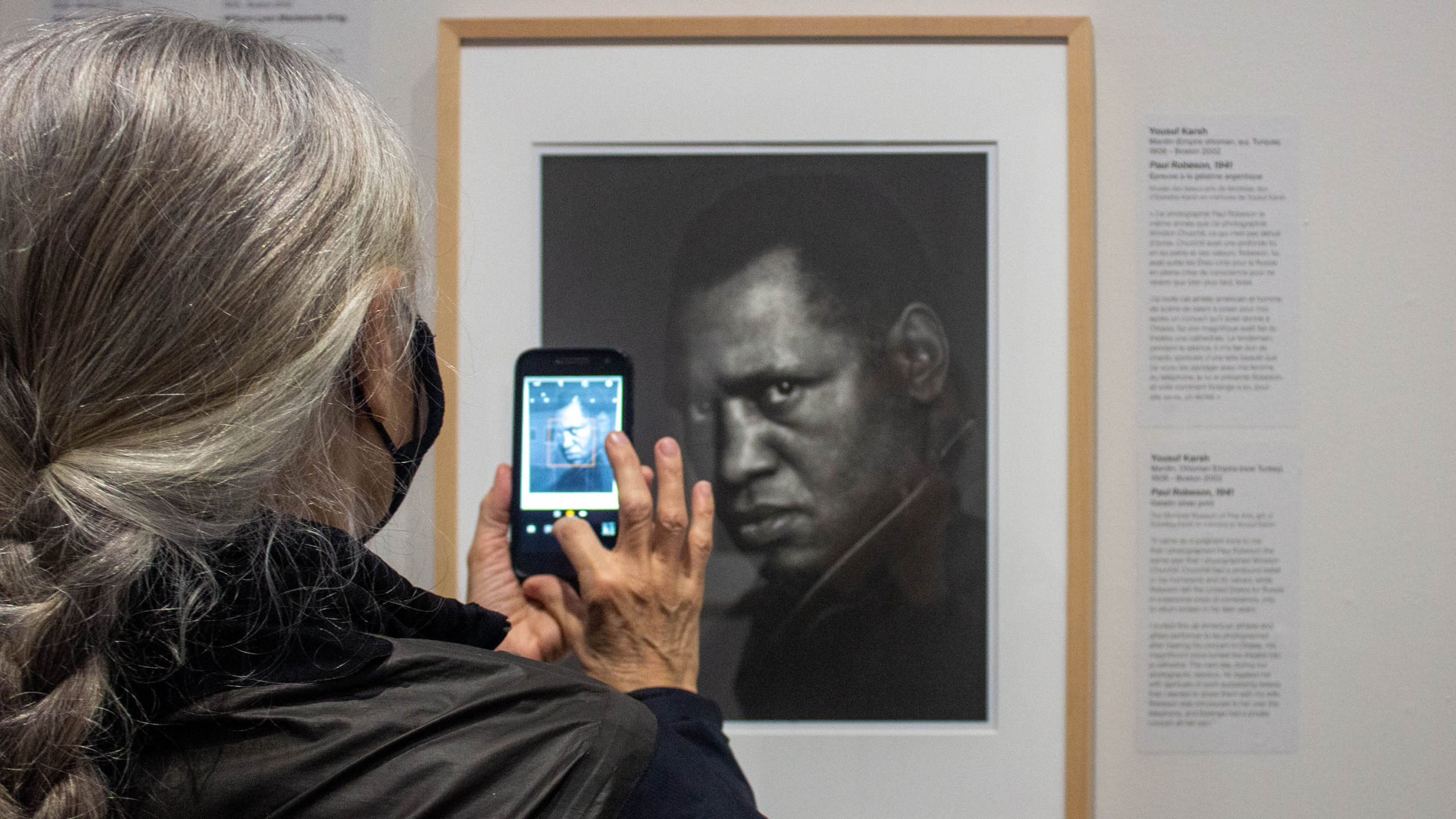 Woman takes a picture of a portrait on her phone.