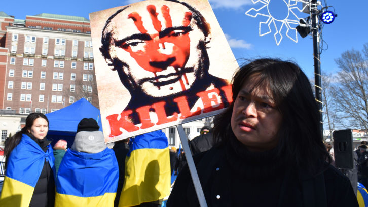 A man holds a sign labeling Russian President Vladimir Putin as “Killer” at the Halifax protest. Other protestors wear Ukrainian flags to show their support. 