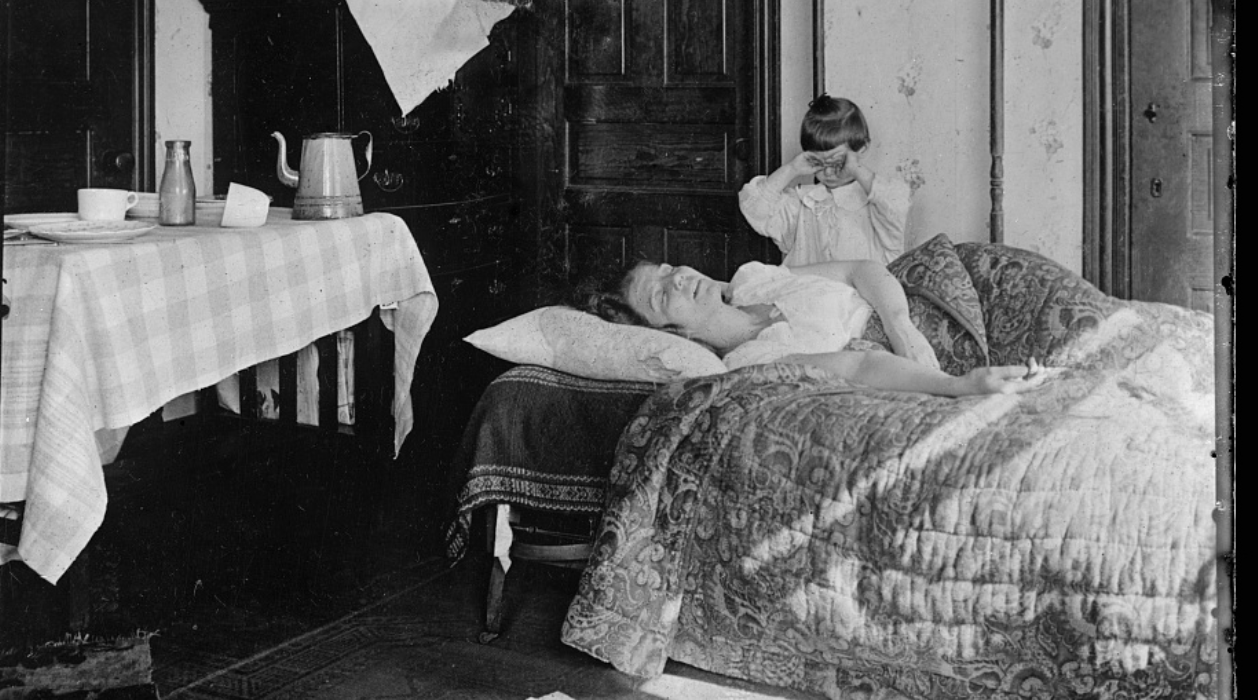 A girl stands beside her sister bedridden with influenza in November 1919.