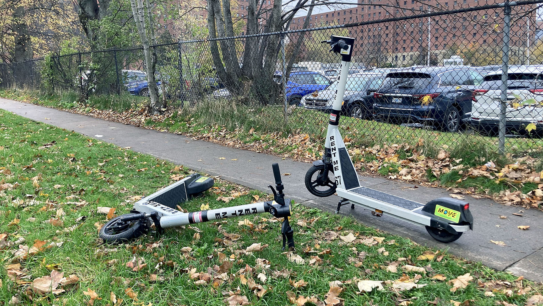 Two e-scooters next to a sidewalk