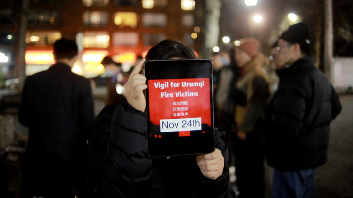 A woman at Halifax’s gathering against China’s Zero-COVID policy holds up a tablet that doubles as a poster, calling attention to the Nov. 24 Urumqi apartment fire. Chinese characters on the image read “Mourning our compatriots. Holding the government accountable. Supporting the act of speaking out.” 
