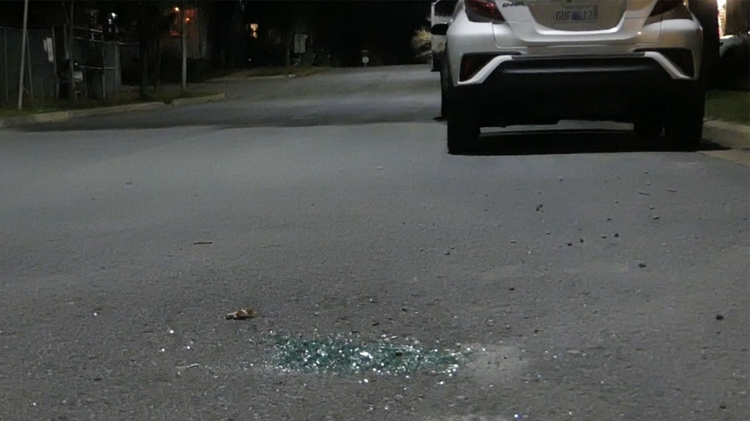 Broken glass outside of a car on the street.