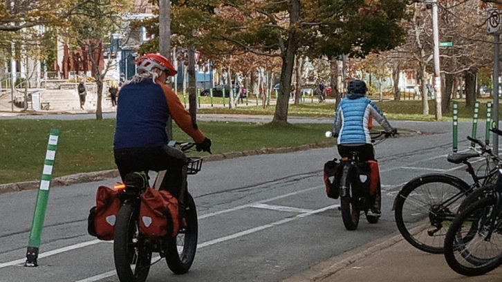 Two cyclists ride down University Avenue using the interim bike lane. 