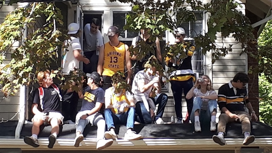 People sit on a roof wearing dalhousie T-shirts. Some people are drinking