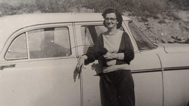 old photo of woman in front of car