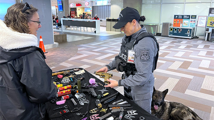 Traveller Penny Irving speaks with Const. Susan Conrad at a display at the Halifax Stanfield International Airport on Monday. Looking on is police dog Mako. The display was to educate travellers on how to best avoid pre boarding delays.