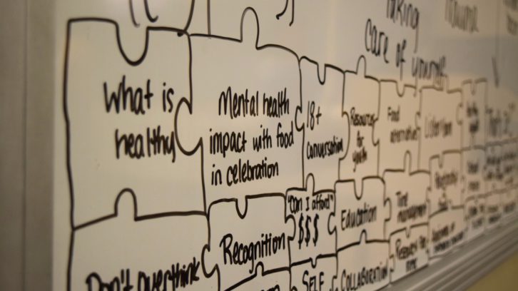 Handwritten notes in black dry-erase marker are filled on a whiteboard, describing takeaways the attendees mentioned during this conversation. 