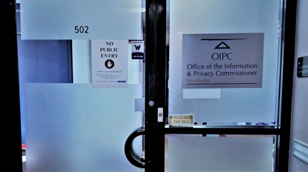 A glass door has two paper signs that say “No public entry” and “Office of the Information and Privacy Commissioner.” 