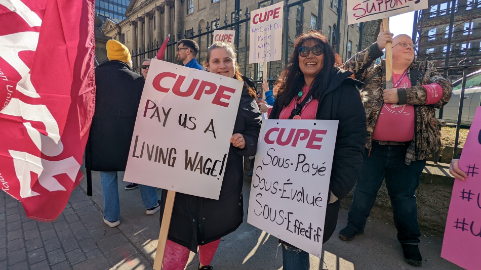 Protestors hold CUPE branded signs calling for higher wages in front of Province House in Halifax.