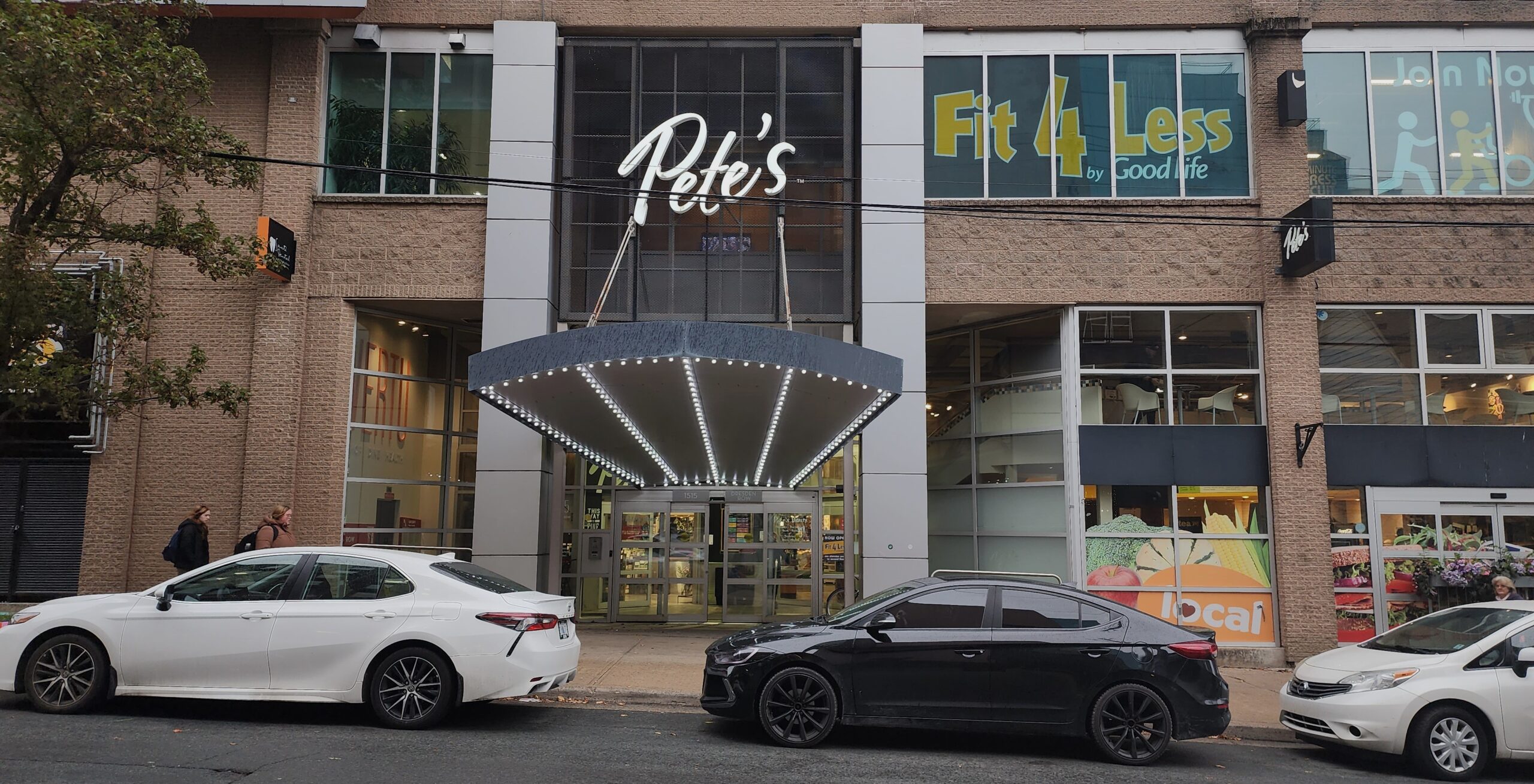 Pete's sign on storefront with cars in foreground