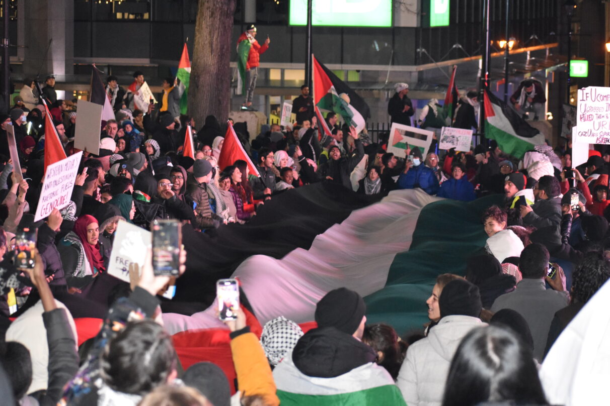 Crowd gathered around a Palestinian flag