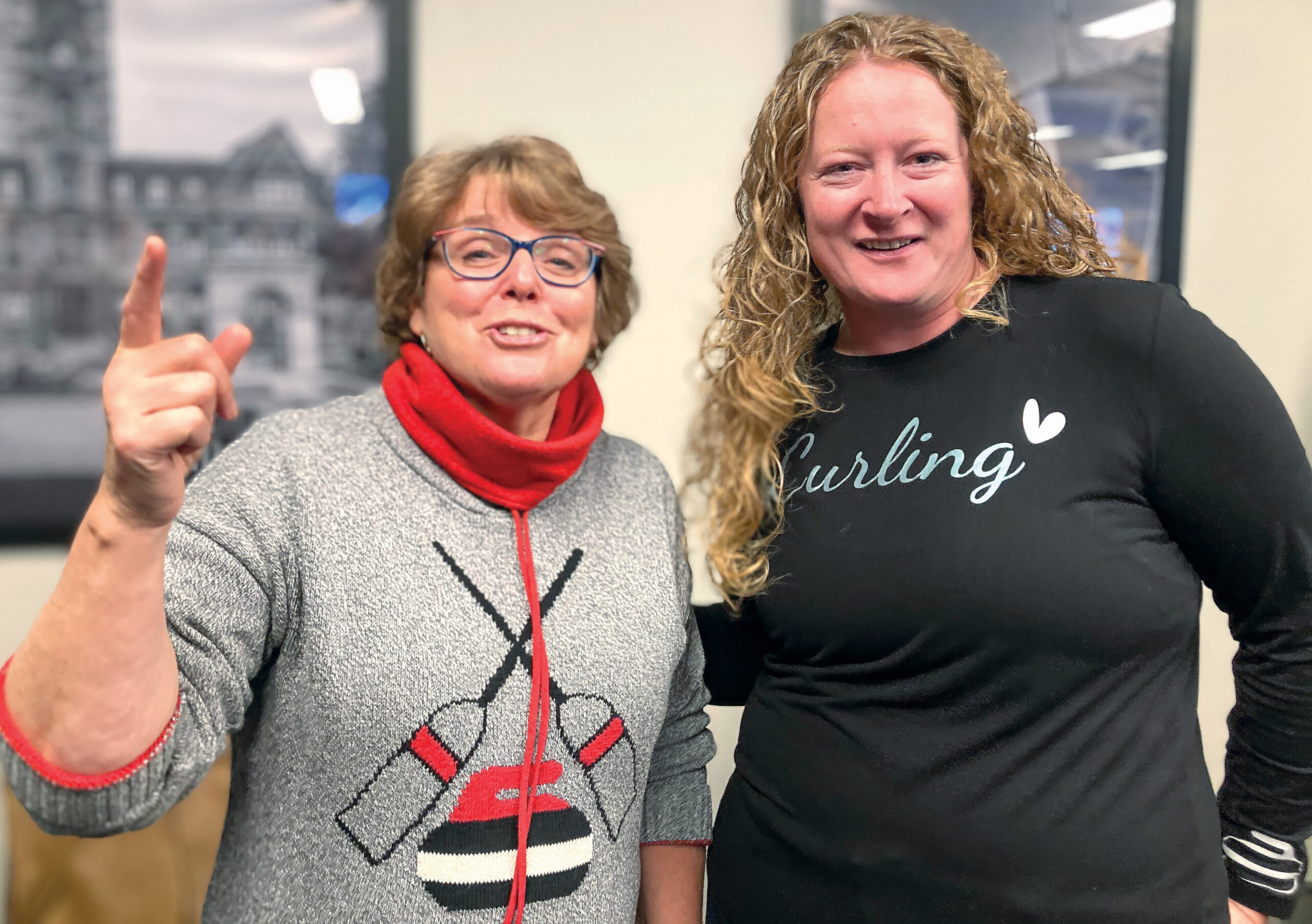 Two women wearing Curling themed sweater smiling for the camera
