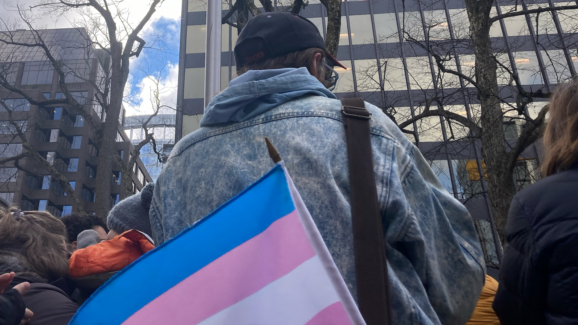 Man with back turned with transgender flag poking out of back pocket.