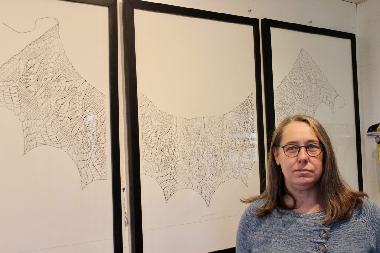 Artist poses in front of her work on display.