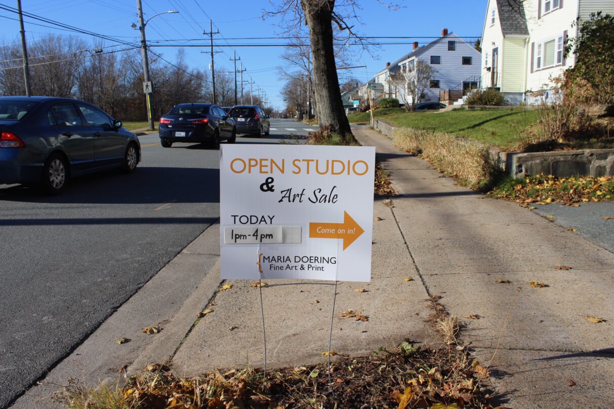 Sign on side of road reads "open studio and art sale."