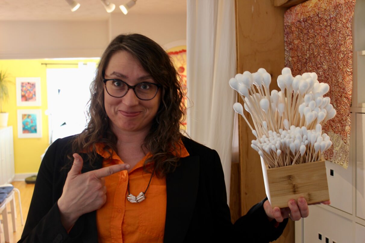 Woman points to a box full of large Q-tip-like art tools.