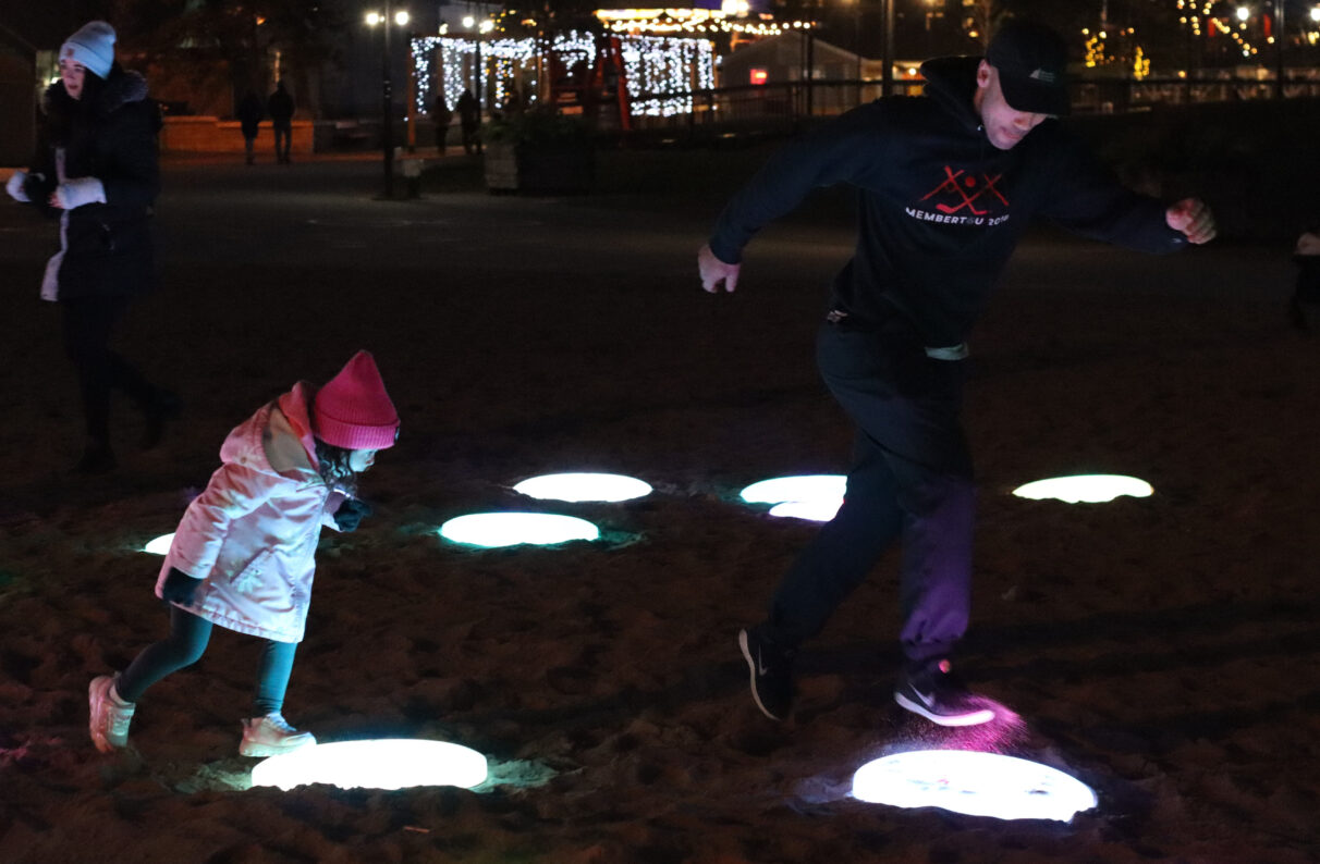Little girl and Man jumping on glowing pebbles.