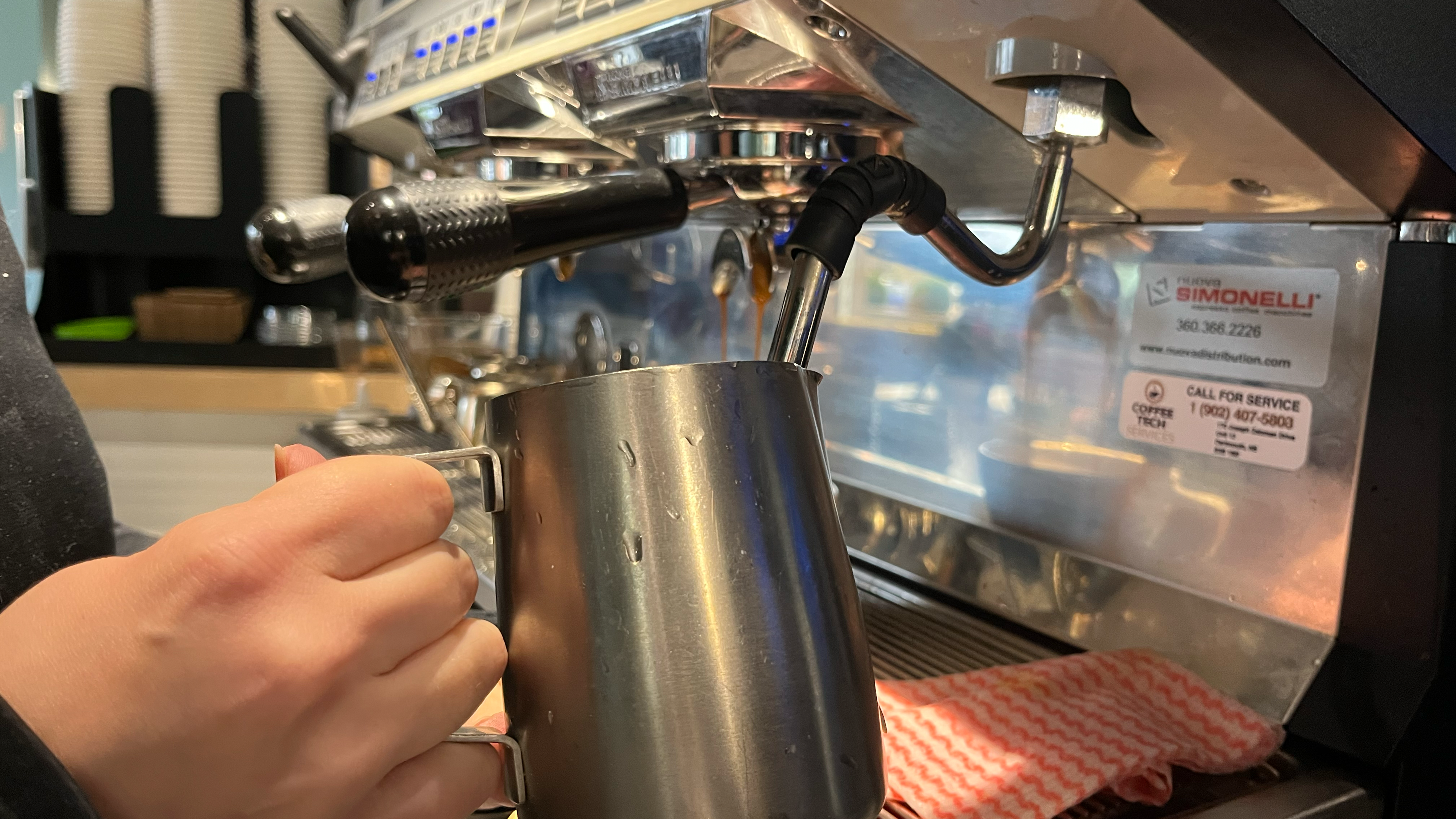 A barista steams milk for latte on an espresso machine at a Halifax coffee shop.