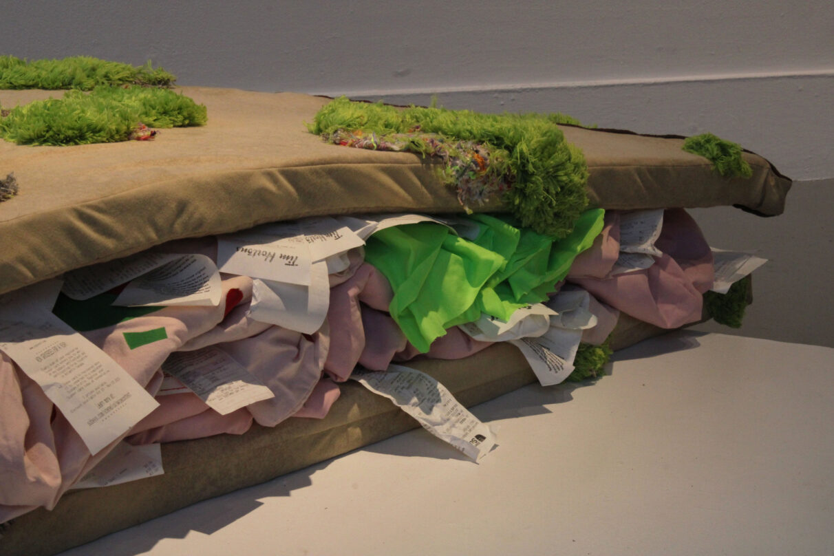 An over-sized sandwich made out of foam mats, bed sheets, reusable grocery bags and bathmats.