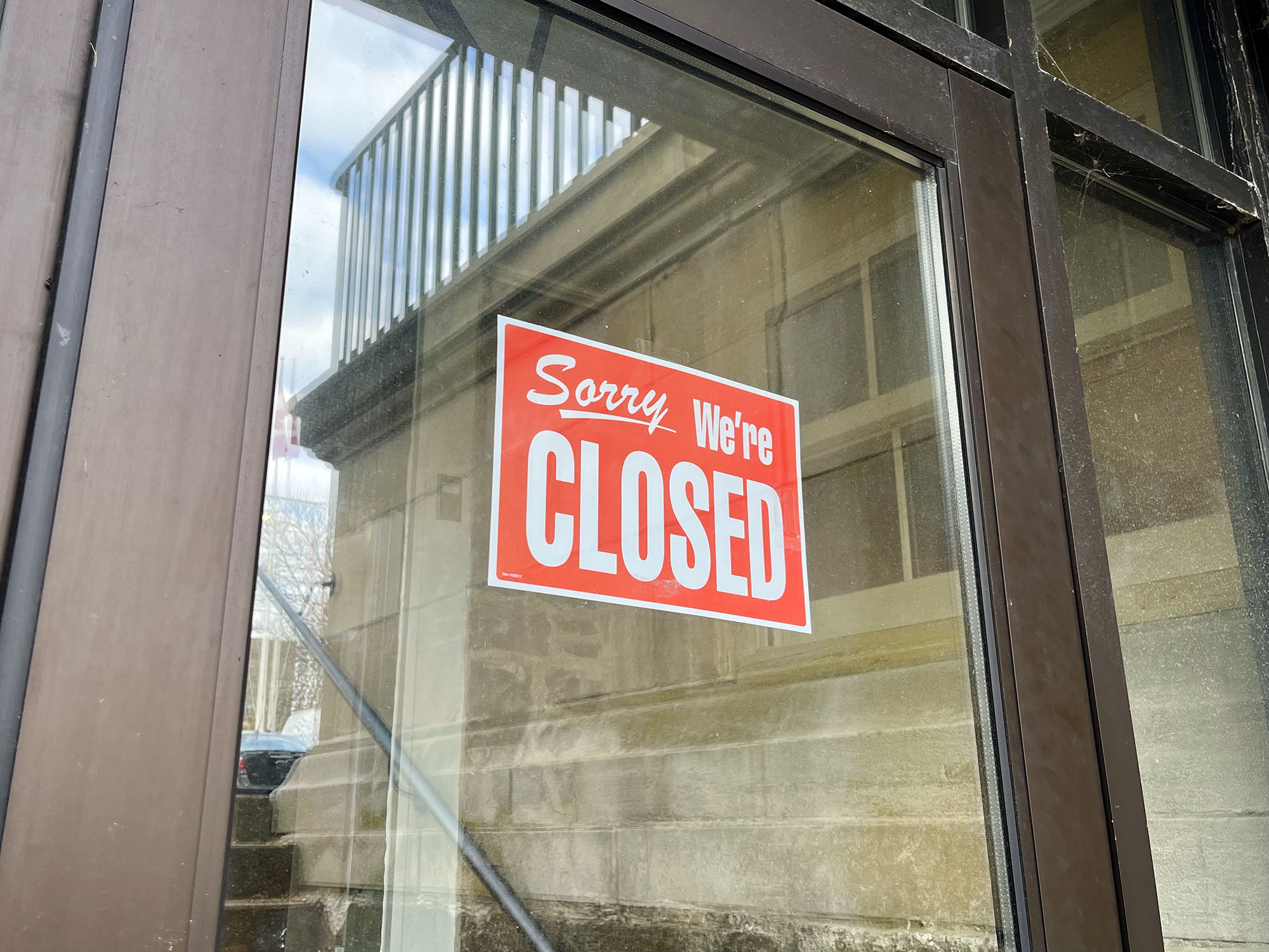 A "Sorry, we're closed sign" is seen on a door.