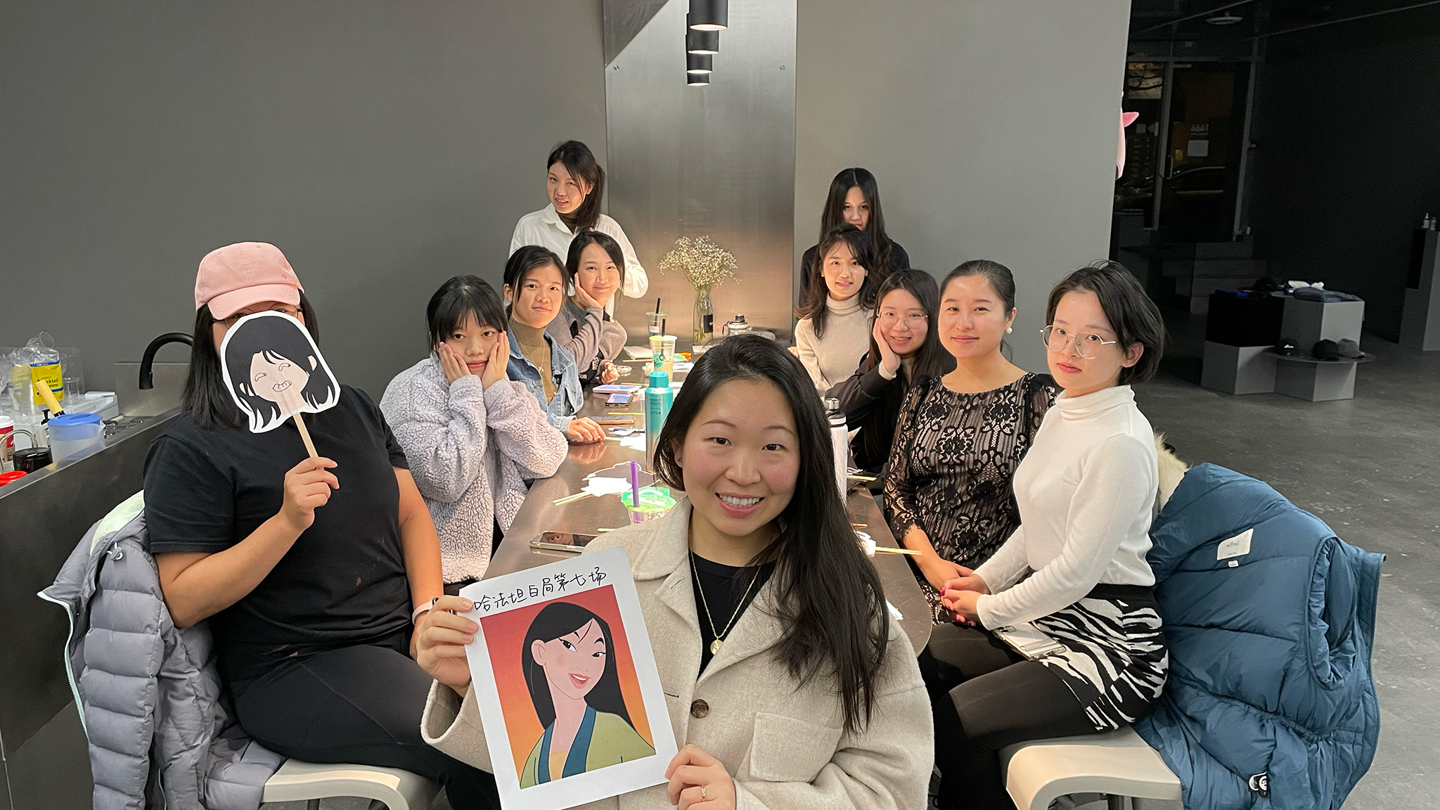 Woman holds image of Mulan with group at table