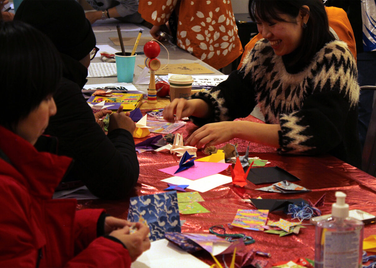 People sitting at a table making origamis.