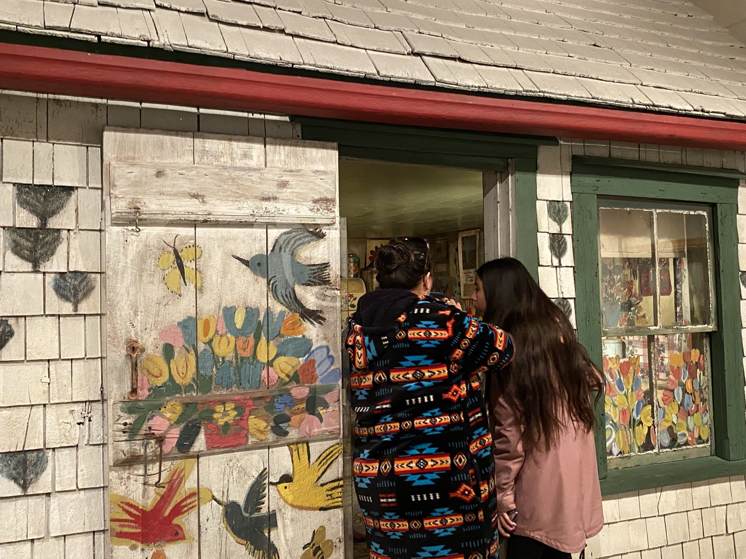 Two people standing in front of the Maud Lewis house in the Art Gallery of NS