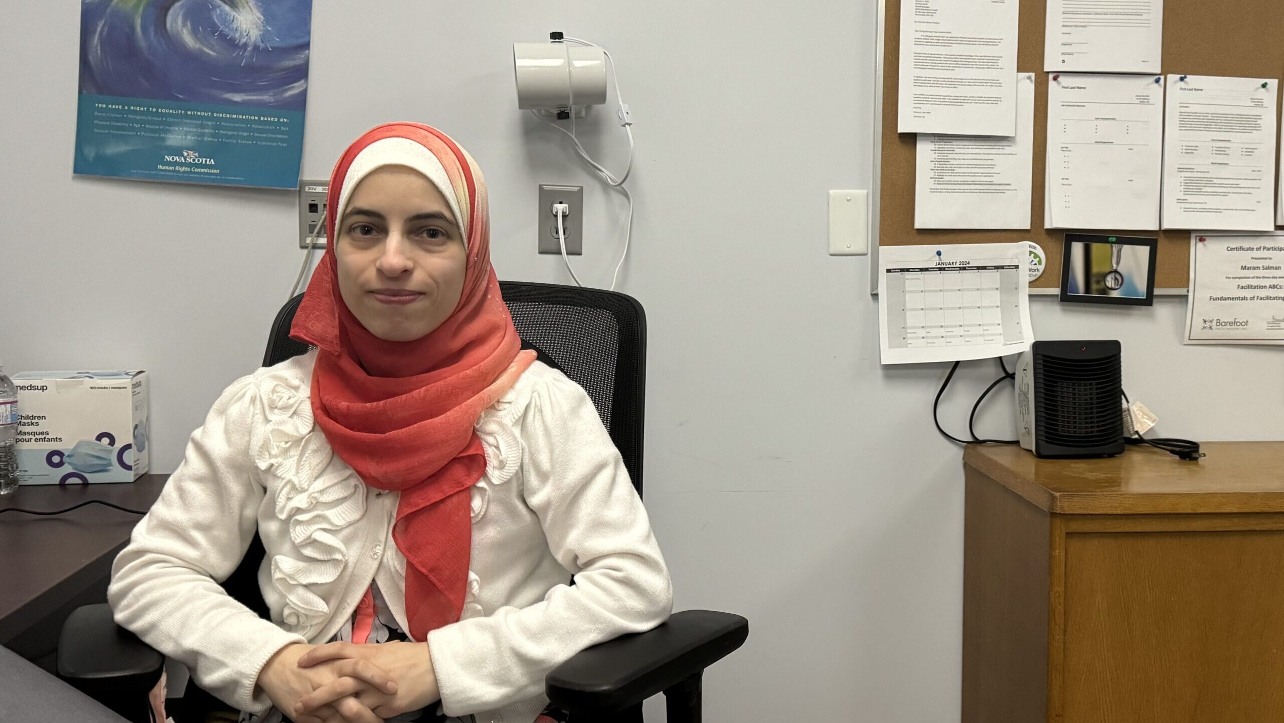 Woman in a hijab sits at her desk.