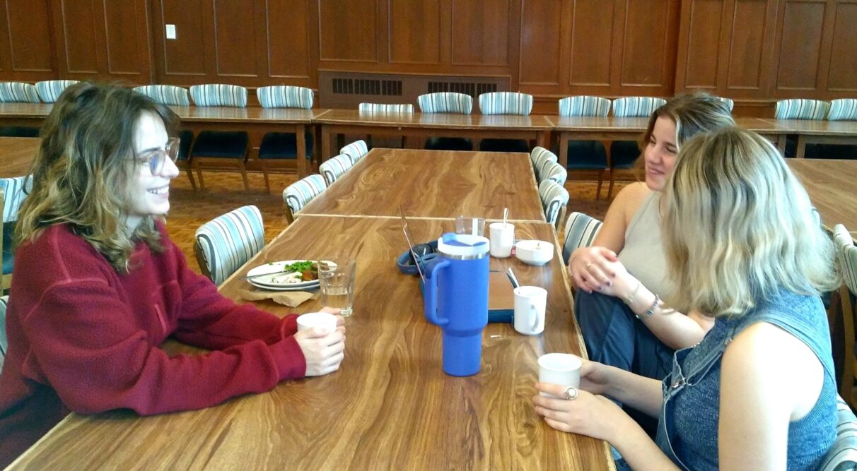 Three women talk in a cafeteria