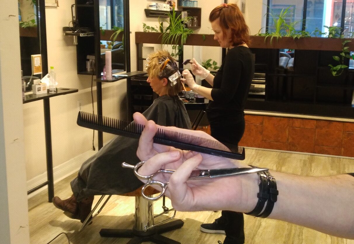 A hair stylist bleaches a client's hair in a salon
