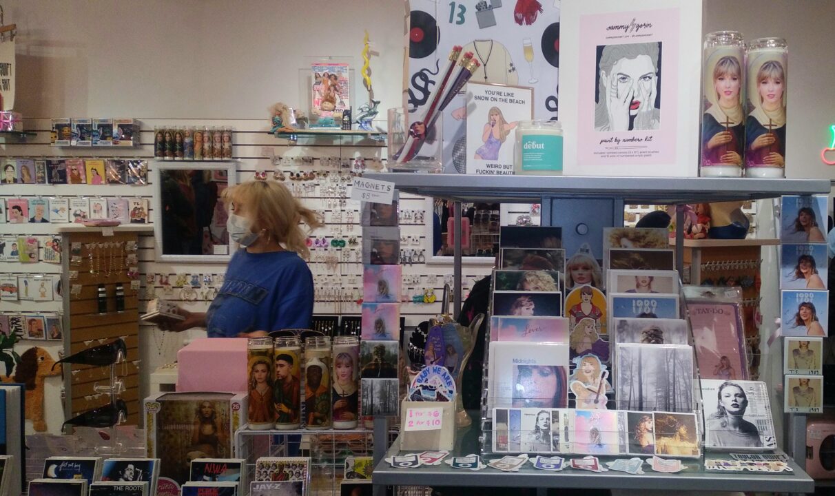 Taylor-Swift merchandise crowds a display shelf in a store.