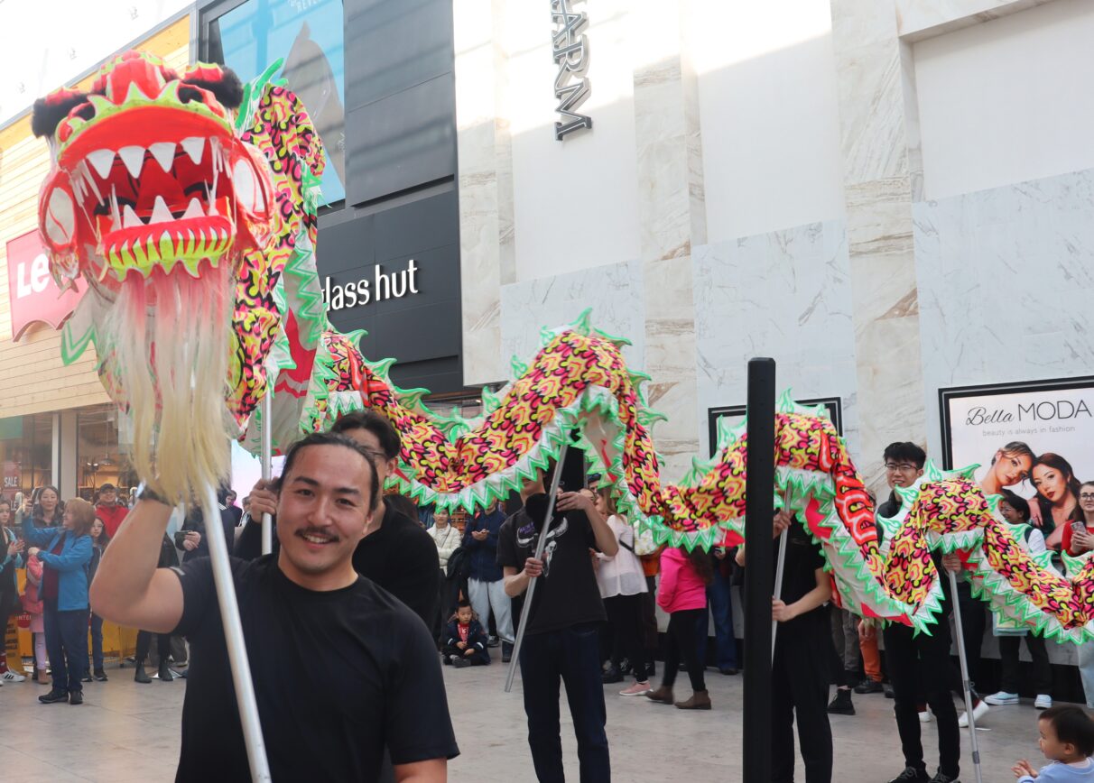 The leading man holds the puppet dragon's head and smiles.