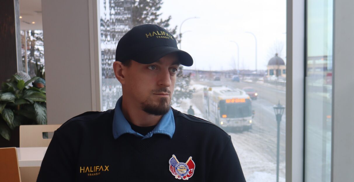 A man wearing a Halifax Transit uniform with a Halifax bus behind him