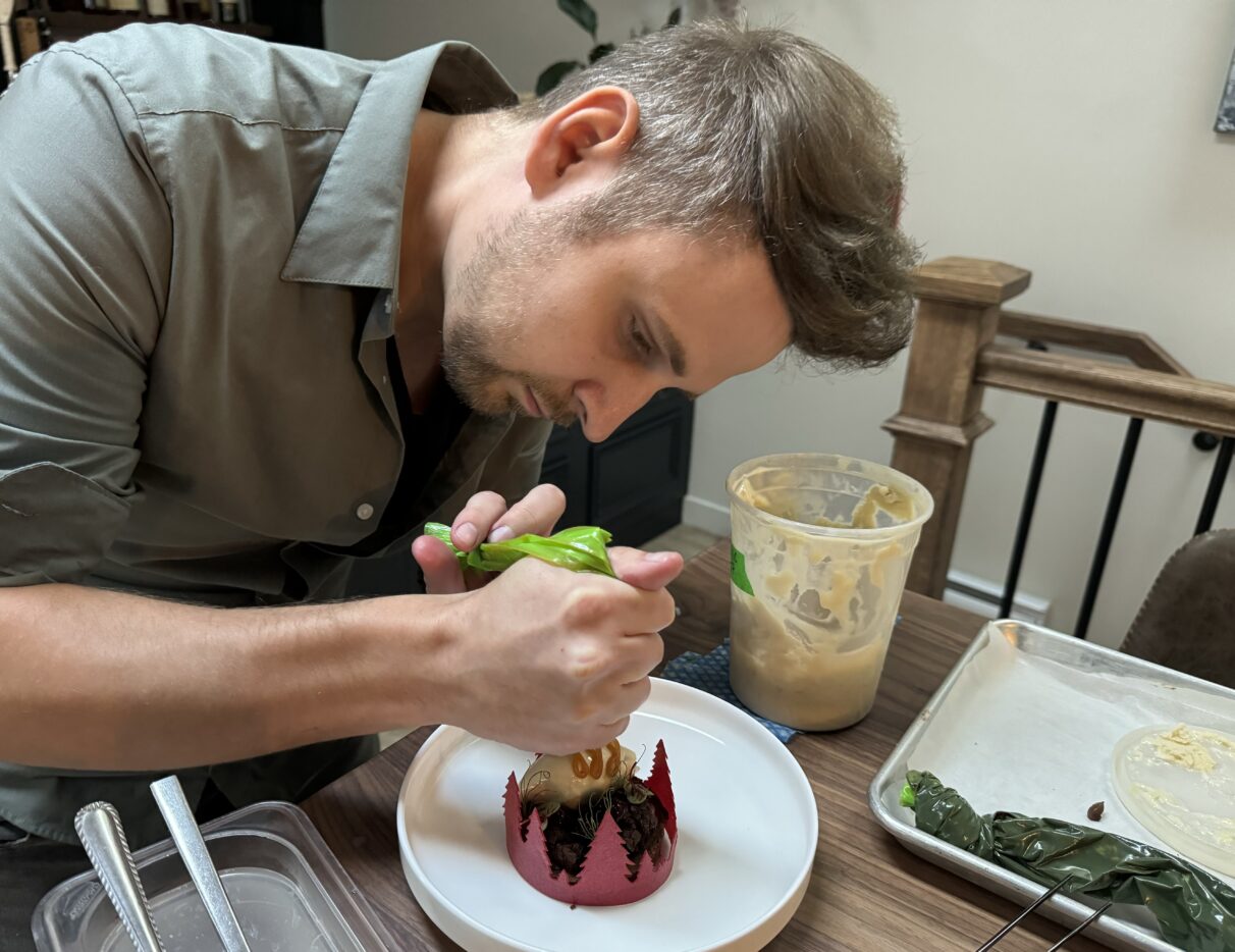 Man in a green shirt prepares a chocolate ganache dessert.