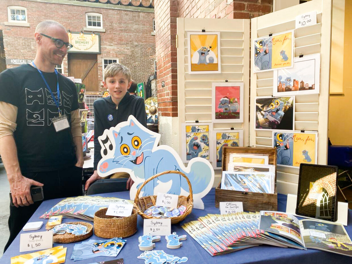 Nathan Little and his son Asher had a booth at Ret-Con to sell artwork of Sydney the Song Cat.
