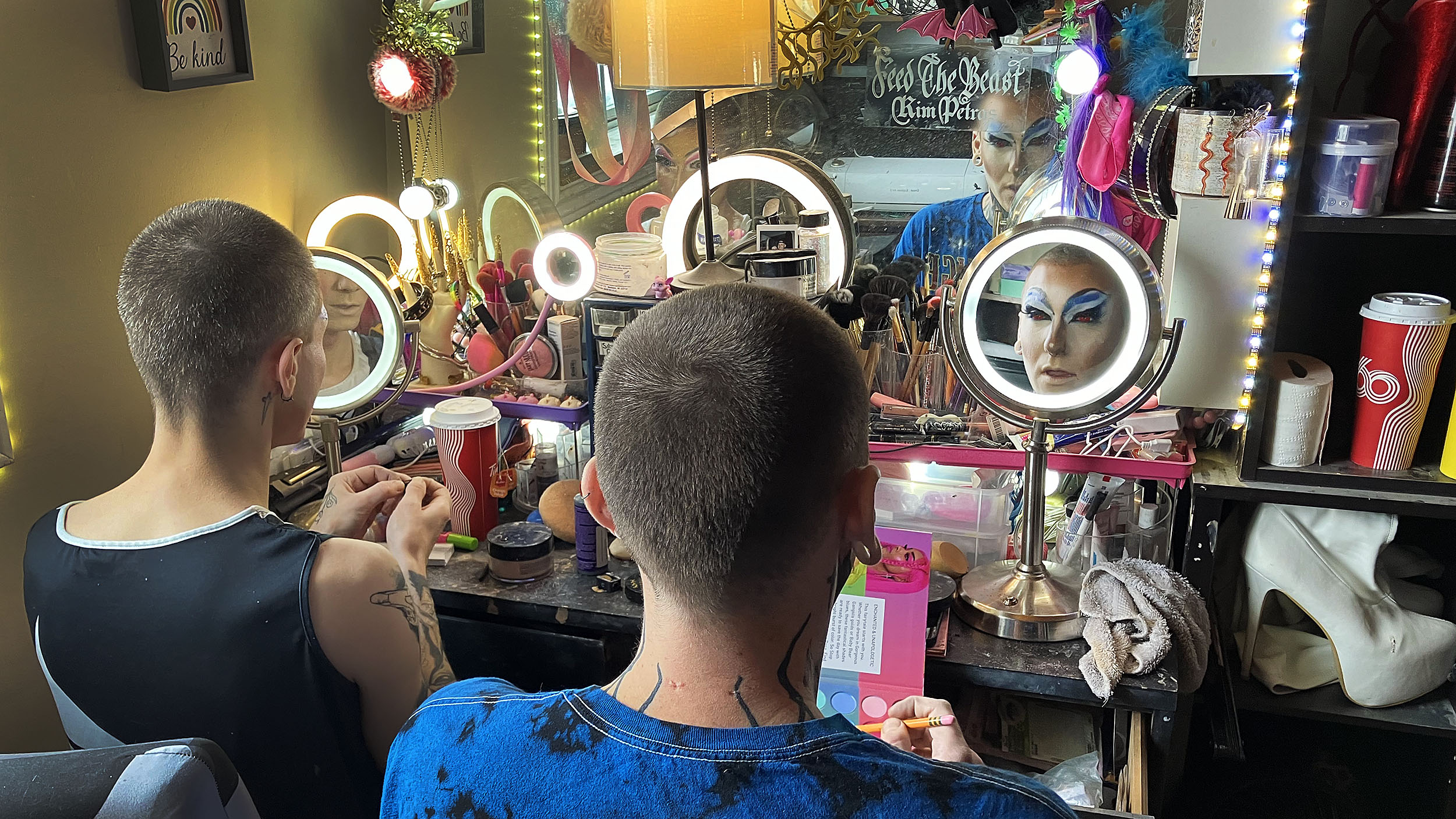 Two drag performers put on makeup.