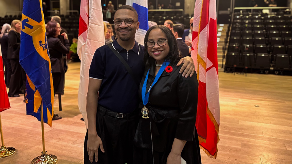 A mother and son standing in front of flags in an auditorium.