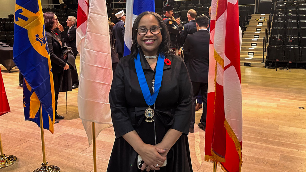 A woman standing in front of flags in an auditorium.