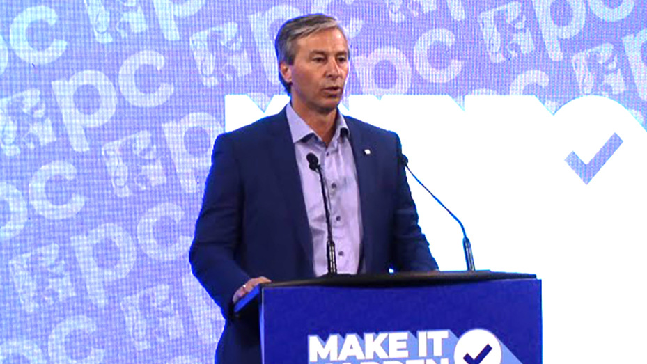 Premier Tim Houston at a podium with PC signage in the background