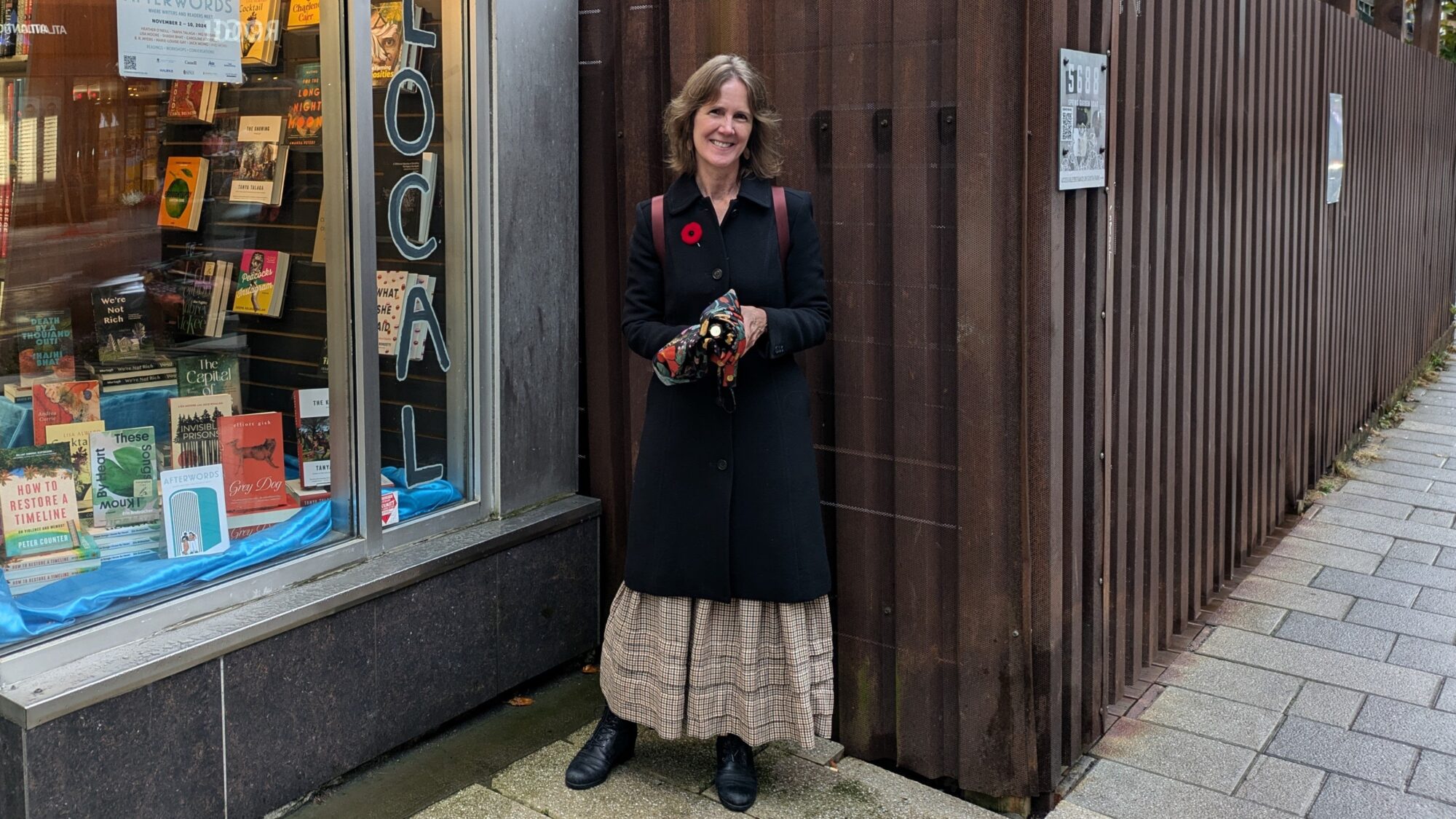 Author Lisa Alward stands in front of a bookstore's window.