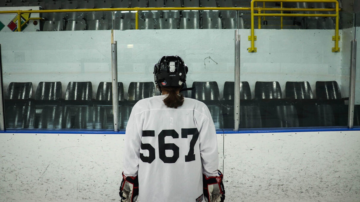 A hockey player stands alone on the ice.  