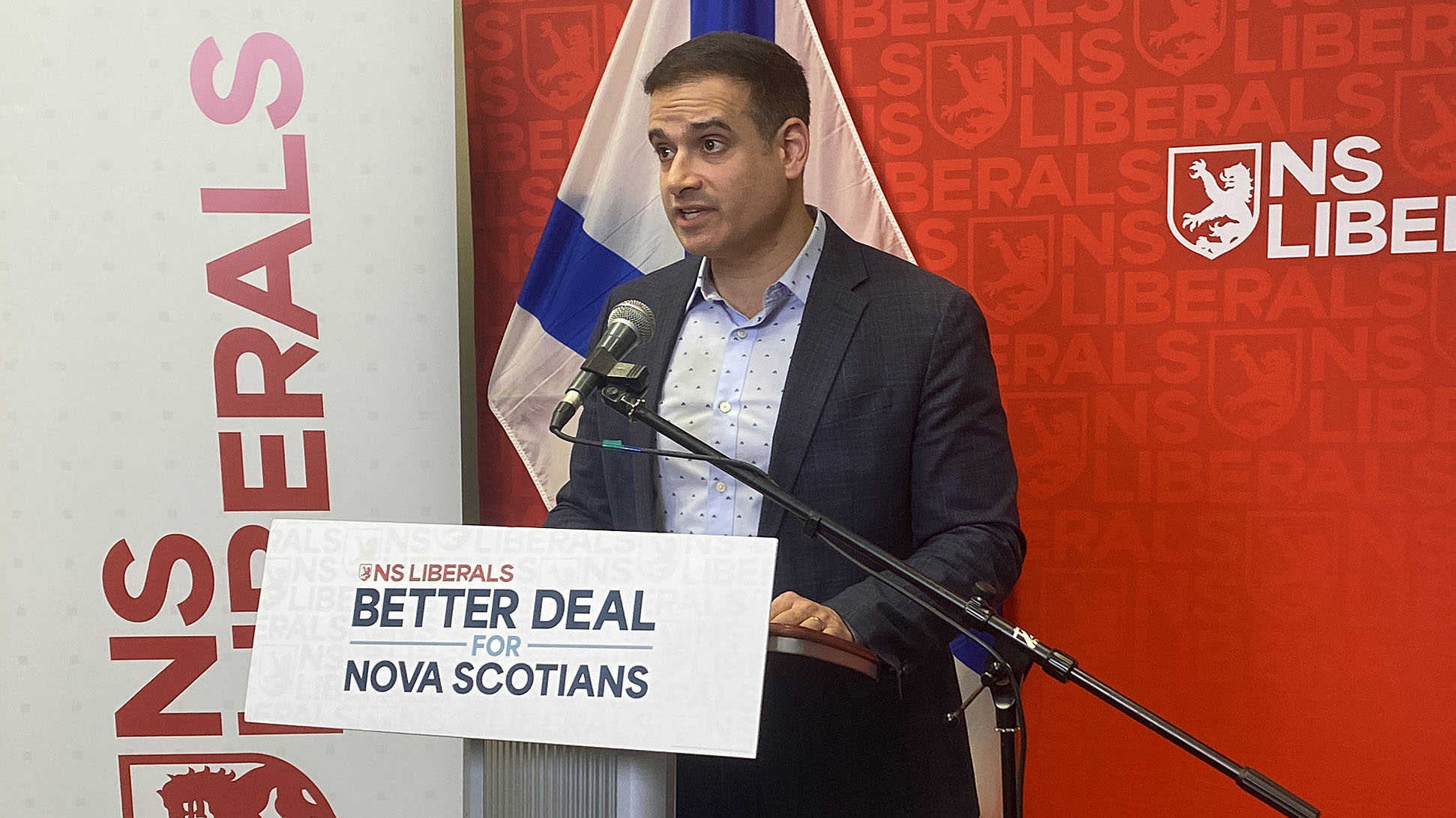 Liberal leader Zach Churchill stands behind podium, red background says "NS Liberals"