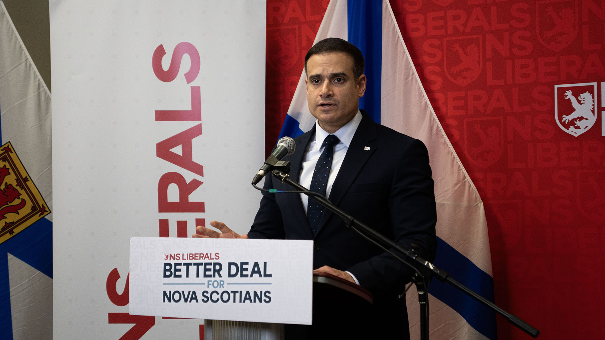 Liberal leader Zach Churchill stands in front of a mic.