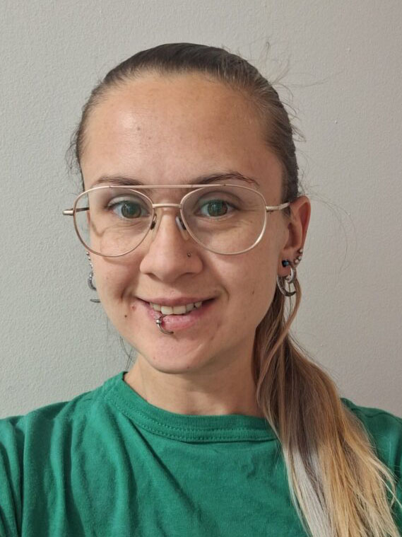 A woman in a green shirt smiles at the camera.