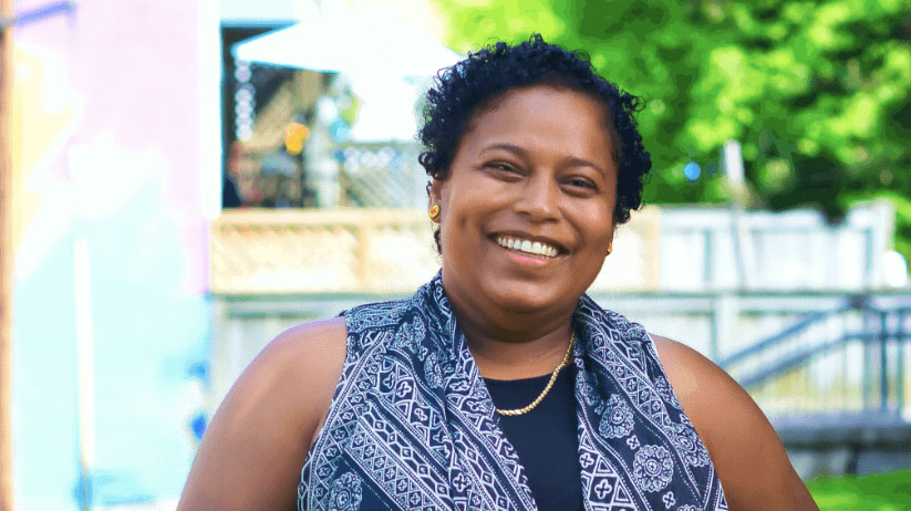 A woman in a blue shirt smiles at the camera.