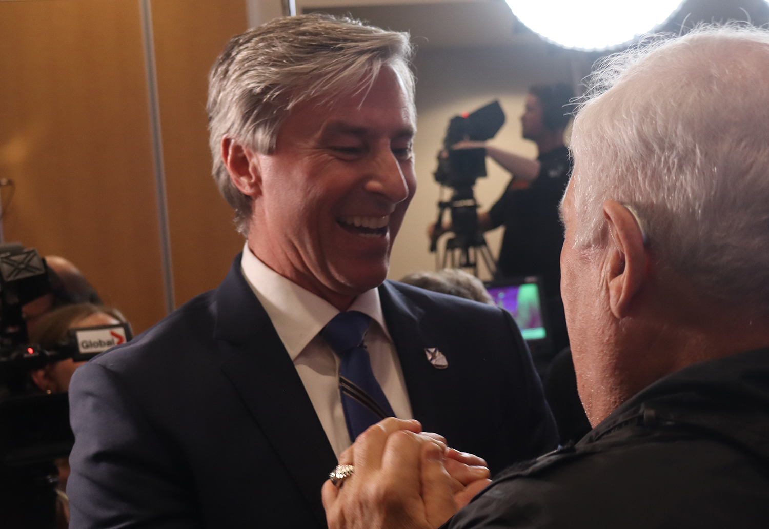 Man smiles as he shakes another man's hand