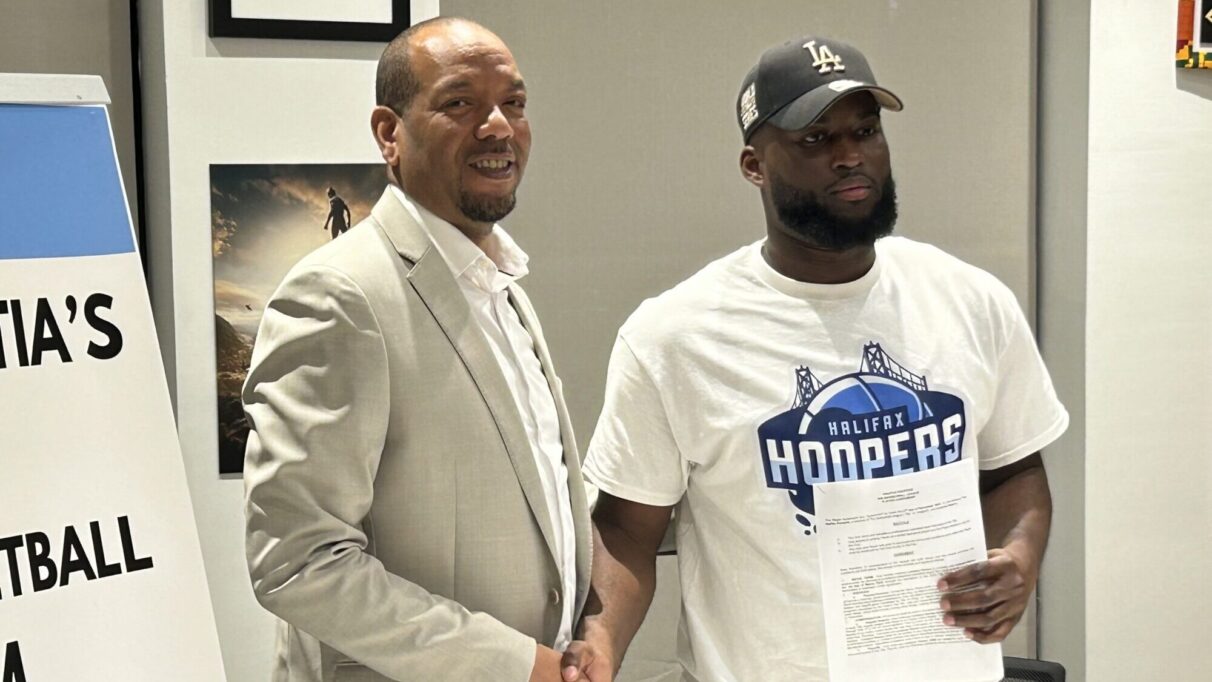 A player holding a contract shakes hands with the team owner